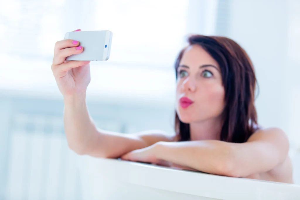 Mujer tomándose una selfie con su celular en un ambiente íntimo